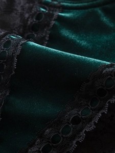 Close-up of emerald green velvet fabric with black floral lace trim detailing