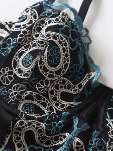 Macro view of blue and silver paisley embroidery on black mesh lace bodysuit