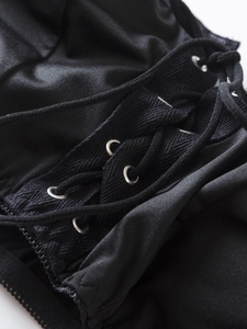 Detailed macro view of black satin fabric with metallic eyelets and criss-cross lacing