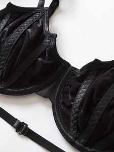 Close-up of black lace bra detail showing fine mesh stitching and satin strip accents