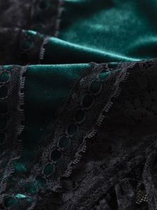 Detail of dark green velvet fabric with intricate black lace trim and stitching