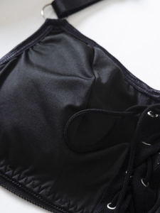 Macro shot of black bikini top featuring metal rings and criss-cross lacing details