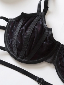 Detail of black and purple lace bra cup showing honeycomb mesh and satin fabric textures