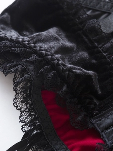 Gros plan du corset en velours noir avec doublure rouge et détails de dentelle fine
