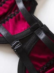 Detailed close-up of adjustable black straps and lace on a dark red satin bra