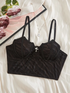 Vue détaillée d'un corset gothique en dentelle noire avec pendentif croix sur du tissu en soie