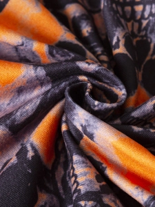 Dettaglio macro della stampa scheletro su body tie-dye arancione e nero in seta di latte