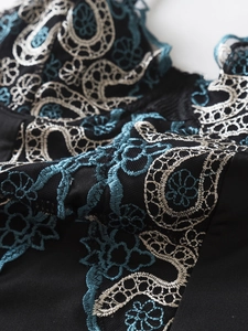 Close-up of intricate light blue floral embroidery on black bodysuit fabric