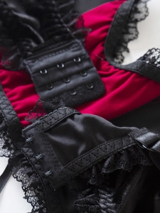 Gros plan détaillé sur l'attache à trois crochets et la texture en dentelle rouge du corset