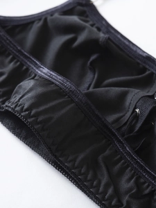 Detail of black satin lingerie with lace trim, elastic straps and silver metal buckles