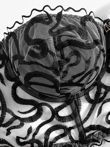 Detail of gothic white mesh corset with black snake pattern embroidery and scalloped lace trim