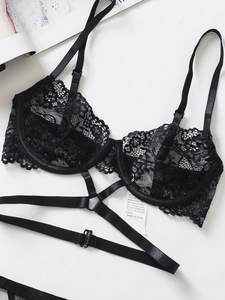 Dettaglio del reggiseno in pizzo nero con ferretto e cinturini incrociati su sfondo bianco