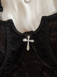 Détail d'un caraco gothique en dentelle noire avec maille fine et pendentif croix argent