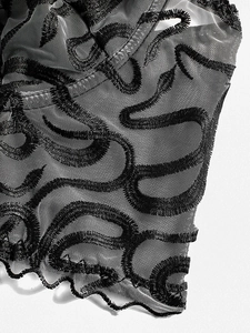 Detail of gothic black mesh corset with snakeskin embroidery and scalloped edges
