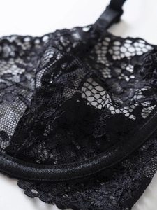 Dettaglio del pizzo floreale trasparente e della lavorazione delicata della lingerie nera