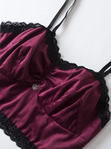 Détail d'un caraco en velours bordeaux avec dentelle noire et pendentif cœur argenté