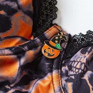 Body di Halloween con stampa teschi, pizzo nero e ciondolo a zucca di strega dettaglio
