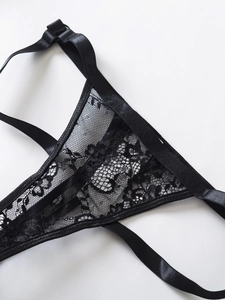 Dettaglio del pizzo floreale nero e del cinturino elastico satinato sul set di lingerie sexy