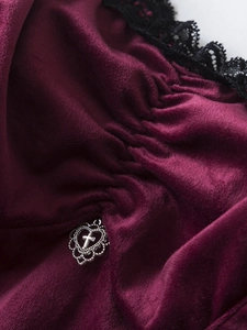 Détail de velours bordeaux avec dentelle noire et pendentif cœur croix argenté