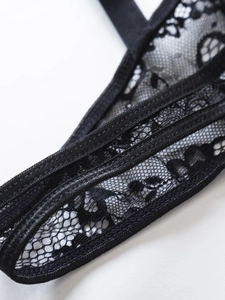 Dettaglio ravvicinato della trama in pizzo floreale nero e cuciture del set lingerie
