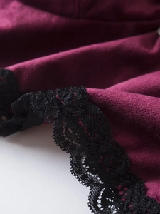 Détail macro du velours bordeaux avec dentelle florale noire délicate sur la lingerie