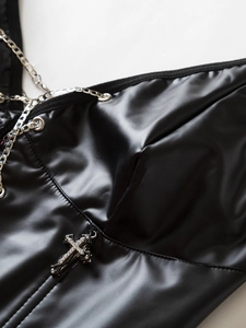 Dettaglio di corsetto in ecopelle nera con catene d'argento e croce di strass luccicanti