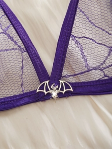 Macro shot of purple lace fabric featuring a silver bat pendant on the sexy bra detail
