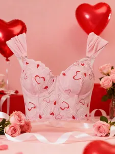 Detailed lace texture of pink corset top with red heart embroidery and ruffled straps