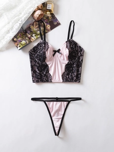 Détail d'un ensemble de lingerie en satin rose avec dentelle noire et nœuds