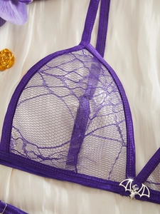 Detail of purple lace bralette with spiderweb pattern and silver bat pendant charm