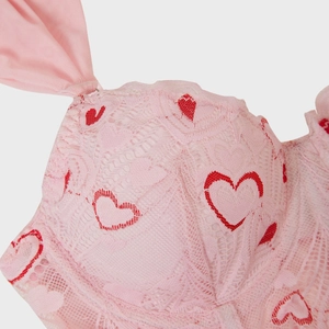 Close-up of pink lace corset featuring delicate red heart patterns and sheer mesh fabric