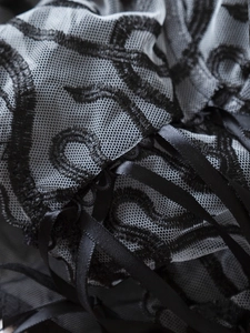 Gros plan sur un tissu de dentelle noire avec broderie et détails de rubans en satin