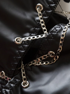 Dettaglio di spalline a catena argento e occhielli metallici su corsetto in pelle PU nera