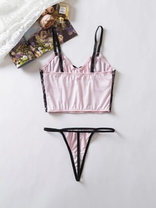 Détail à plat d'un ensemble de lingerie en soie rose avec dentelle noire et petit nœud