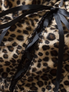 Detailed macro shot of Y2K leopard print velvet fabric with black satin lace-up ribbons