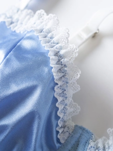 Detailed macro view of light blue satin fabric with intricate white double lace ruffles