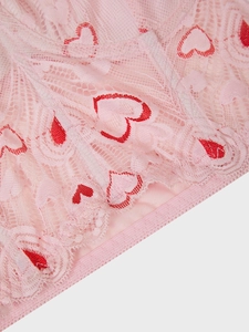 Close-up of pink lace fabric featuring vibrant red heart patterns and mesh texture