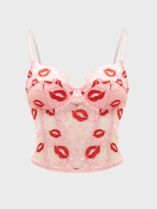 Detailed view of pink lace bustier top with red lip embroidery and mesh texture