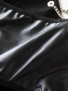Dettaglio di un corsetto in ecopelle nera con catena d'argento e trama in pelle PU