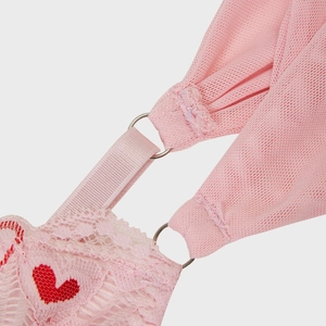 Detailed macro view of pink lace corset with red heart embroidery and metallic ring link