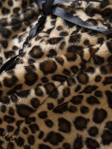 Detailed macro view of leopard print velvet fabric with a black satin bow accent