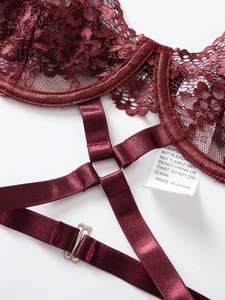 Dettaglio di lingerie in pizzo rosso vino con motivi floreali e cinturini in raso