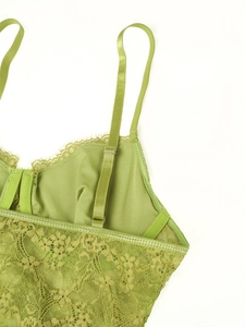 Close-up of adjustable strap and floral lace texture on green camisole top
