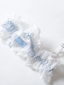 Close-up of white lace garter with blue ribbon detail and adjustable metal buckle