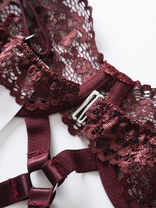 Dettaglio del set di lingerie in pizzo bordeaux con cinturini in seta e fibbie metalliche
