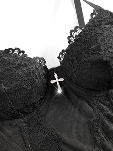 Detail of black lace corset with silver cross pendant and intricate mesh floral embroidery