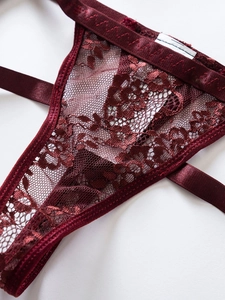 Dettaglio del ricamo in pizzo bordeaux e cinturino in raso su un capo di lingerie