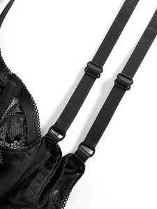 Detail of adjustable double shoulder straps and fine embroidery lace on a black corset top