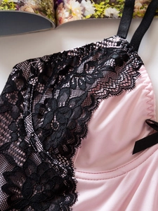 Détail du caraco en soie rose avec dentelle florale noire et petits nœuds élégants