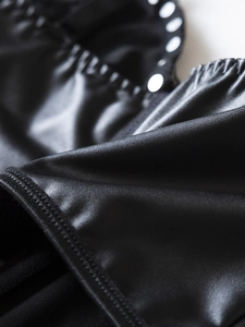 Close-up of black PU leather texture with silver rivet detailing and elastic ruching